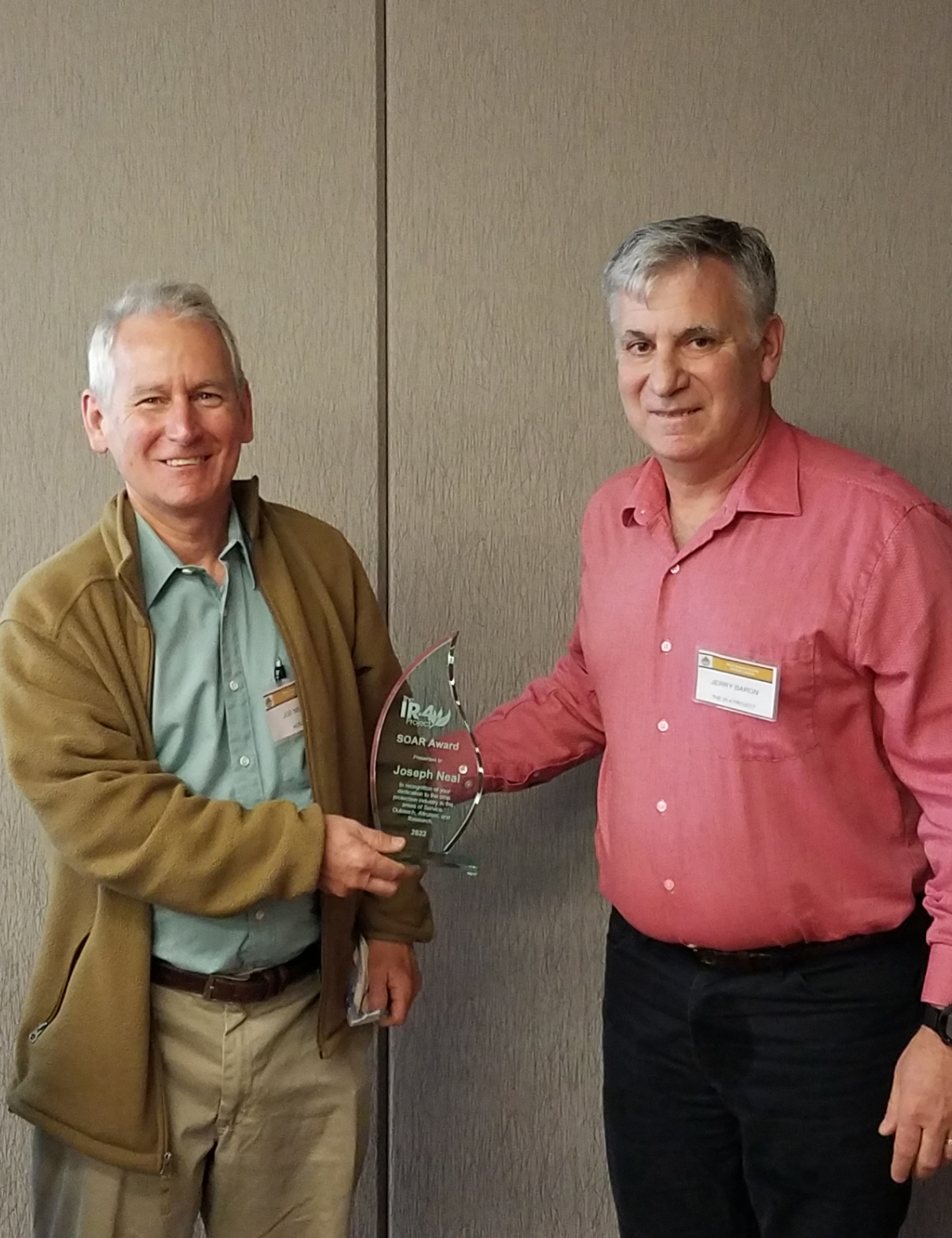 Two men standing in an office holding an award between them.